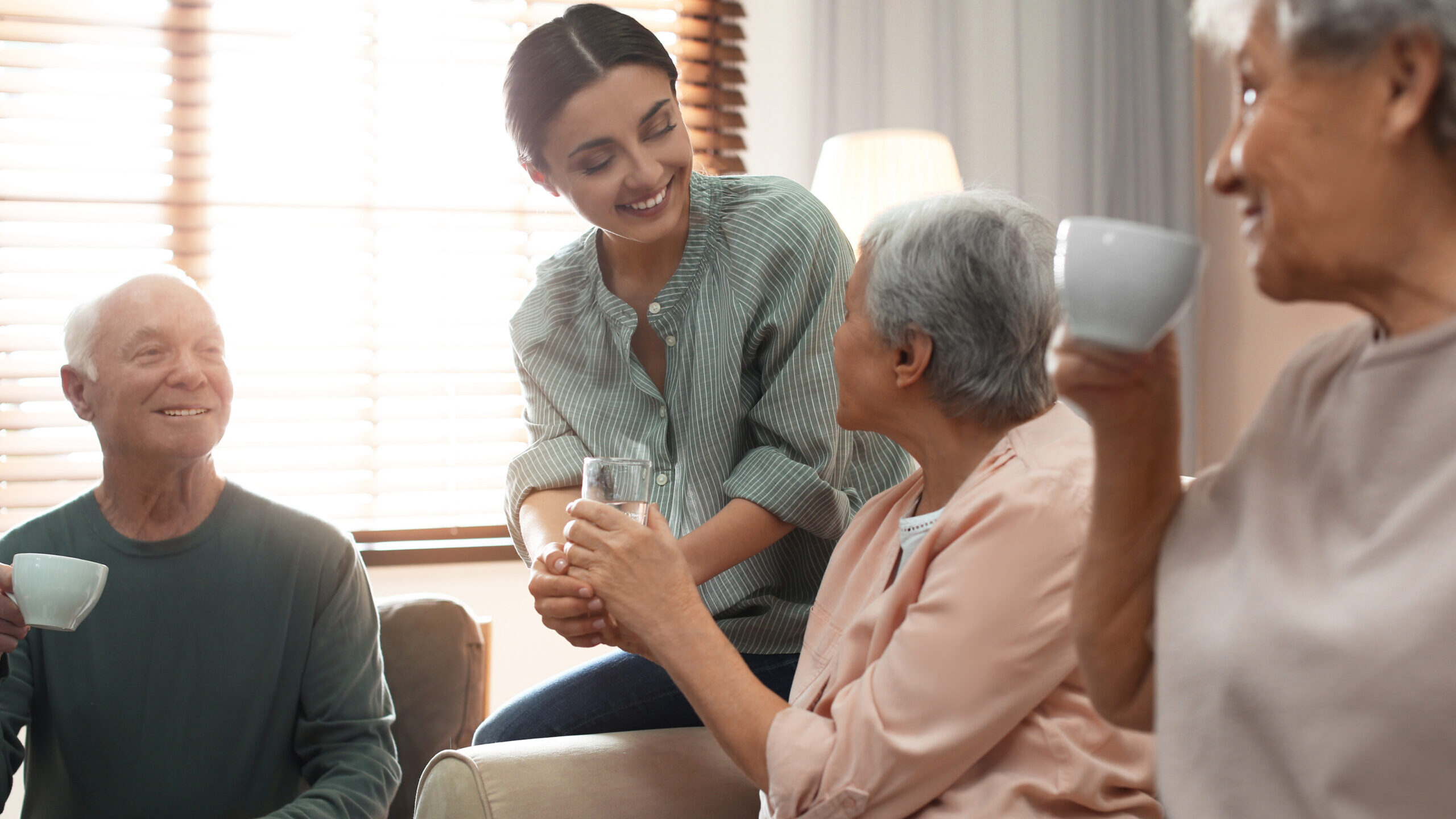 A woman handing someone a drink and holding their hand to steady.