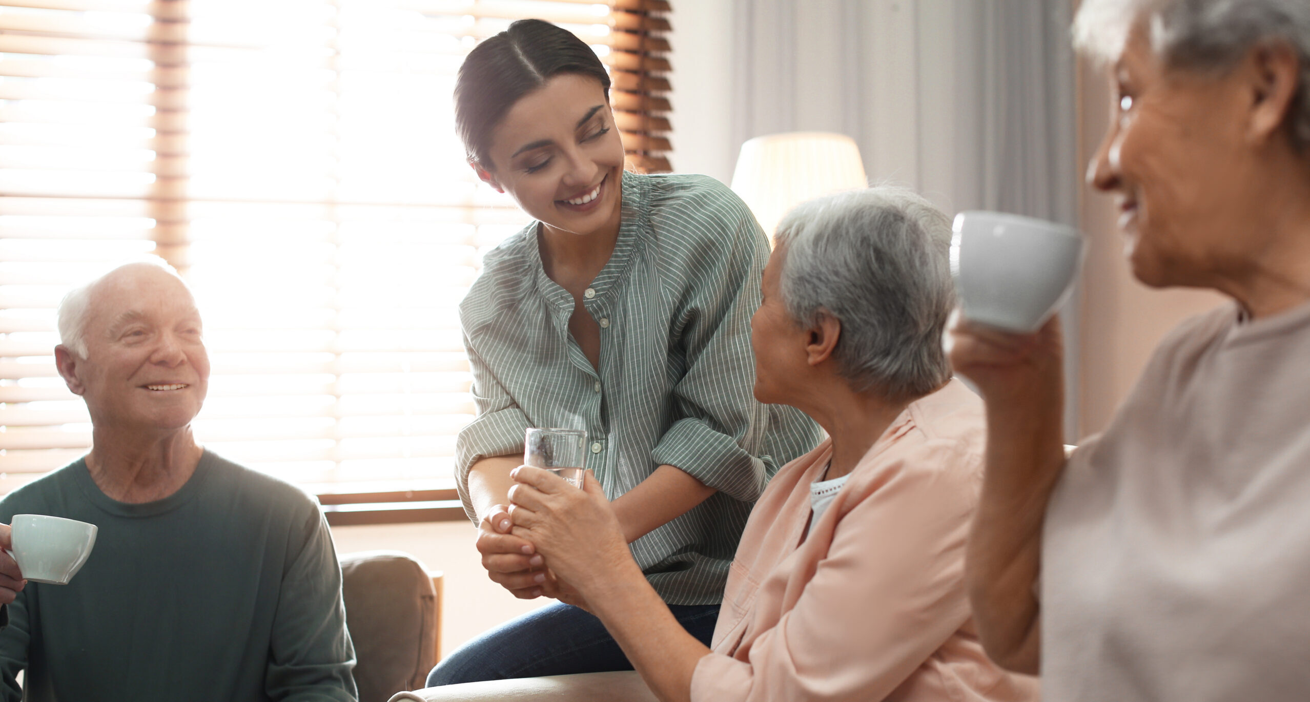 A woman handing someone a drink and holding their hand to steady.