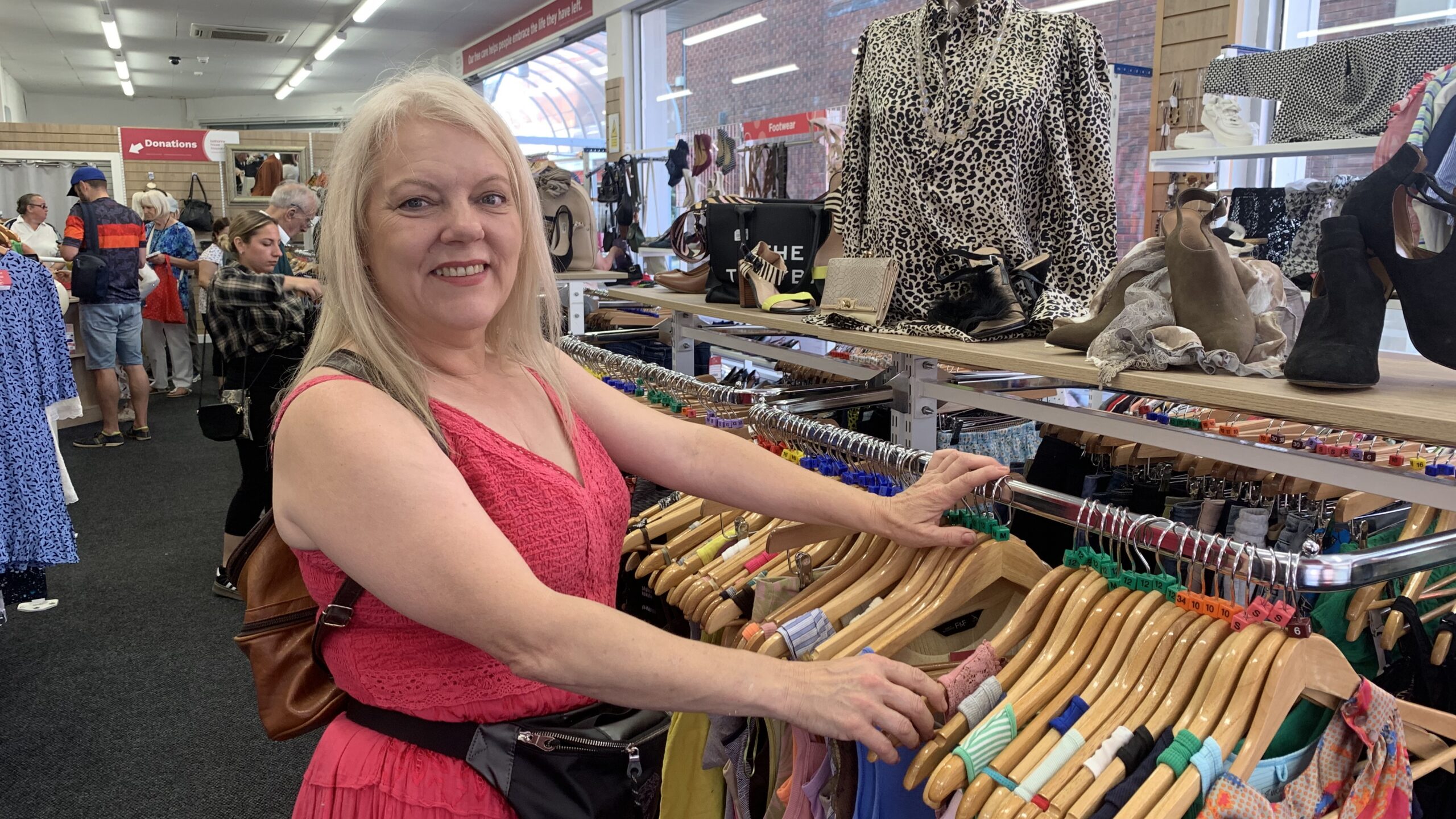 A lady in an orange dress browsing a clothes rail