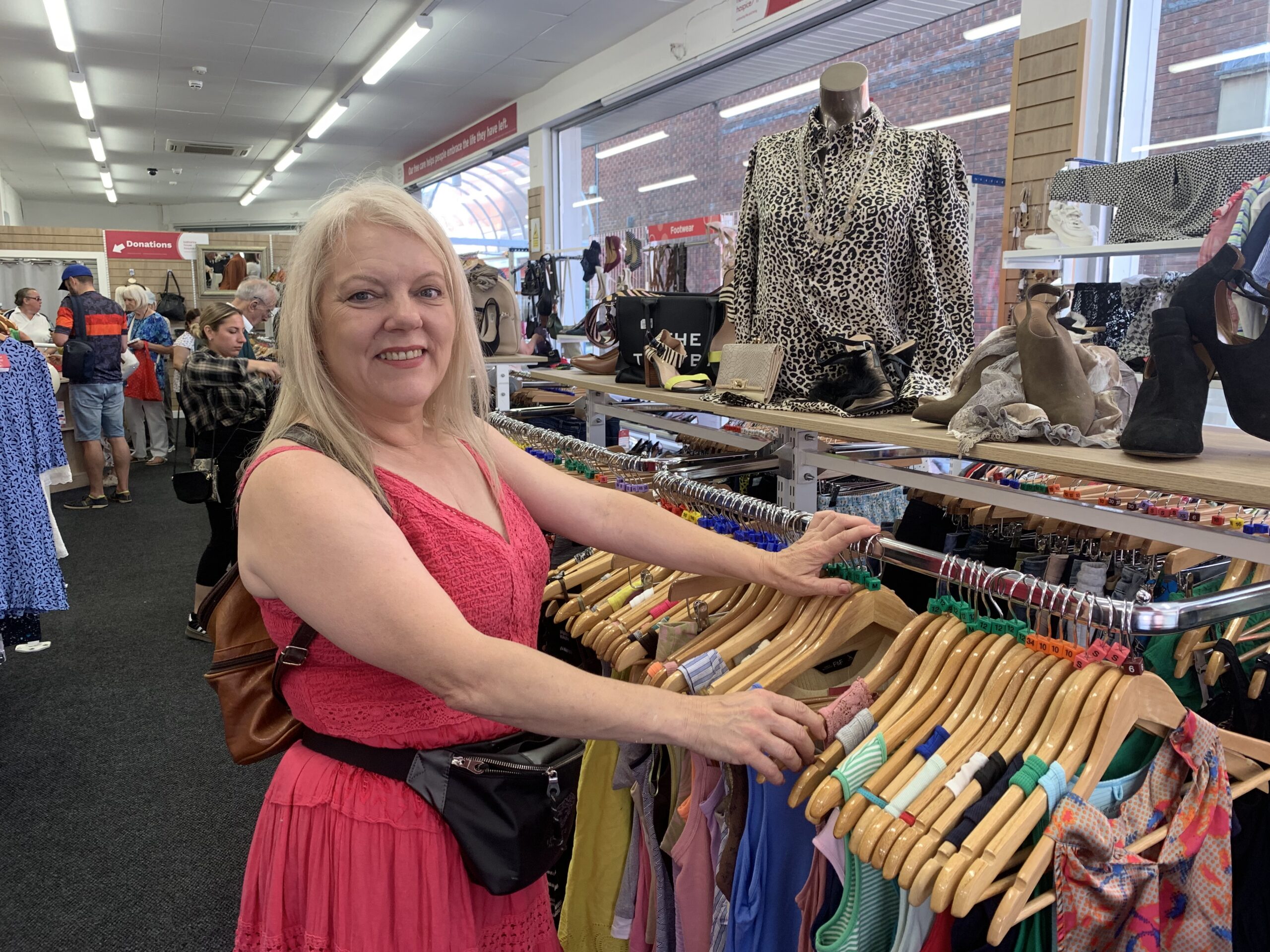 A lady in an orange dress browsing a clothes rail