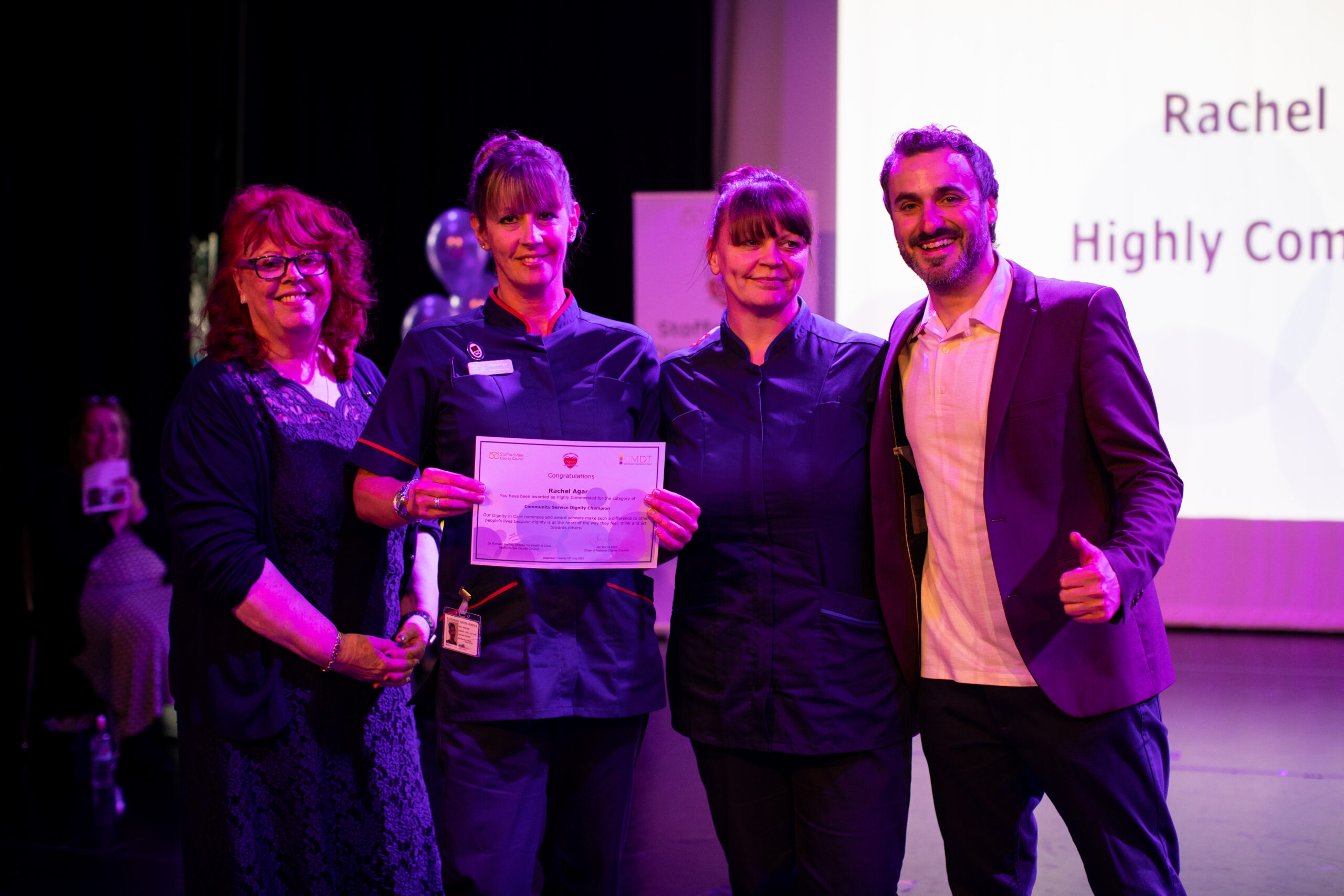 Nurse at award ceremony showing off her certificate.
