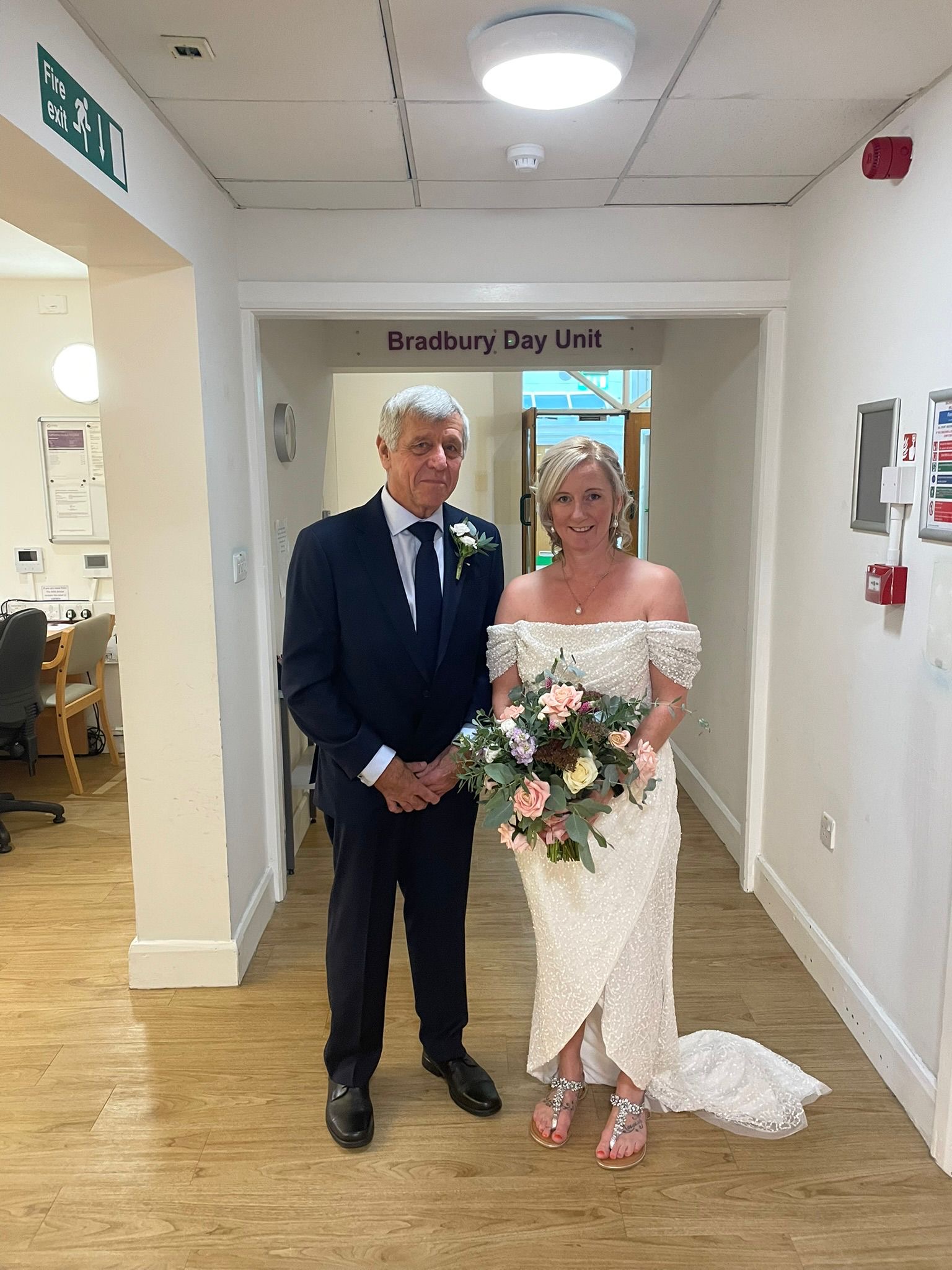A bride and her father smiling together in their wedding attire.