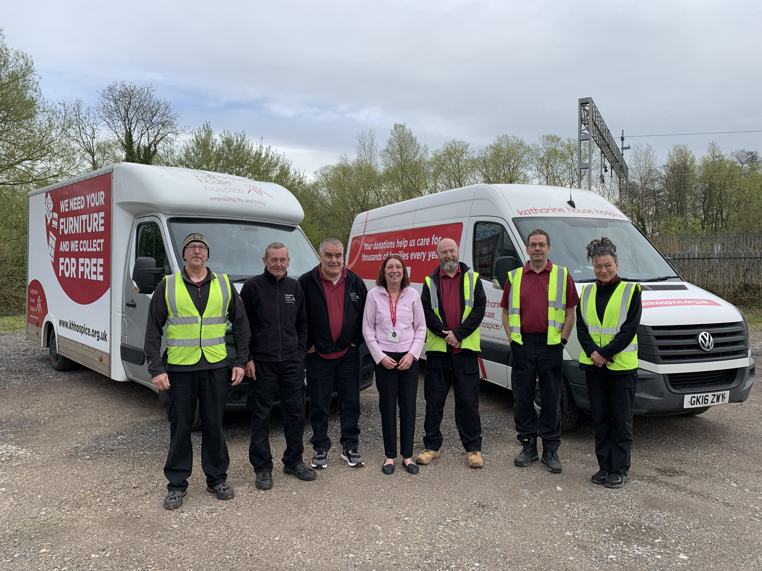 A group of people in hi-vis stand infront of Katharine House Hospice branded vans.