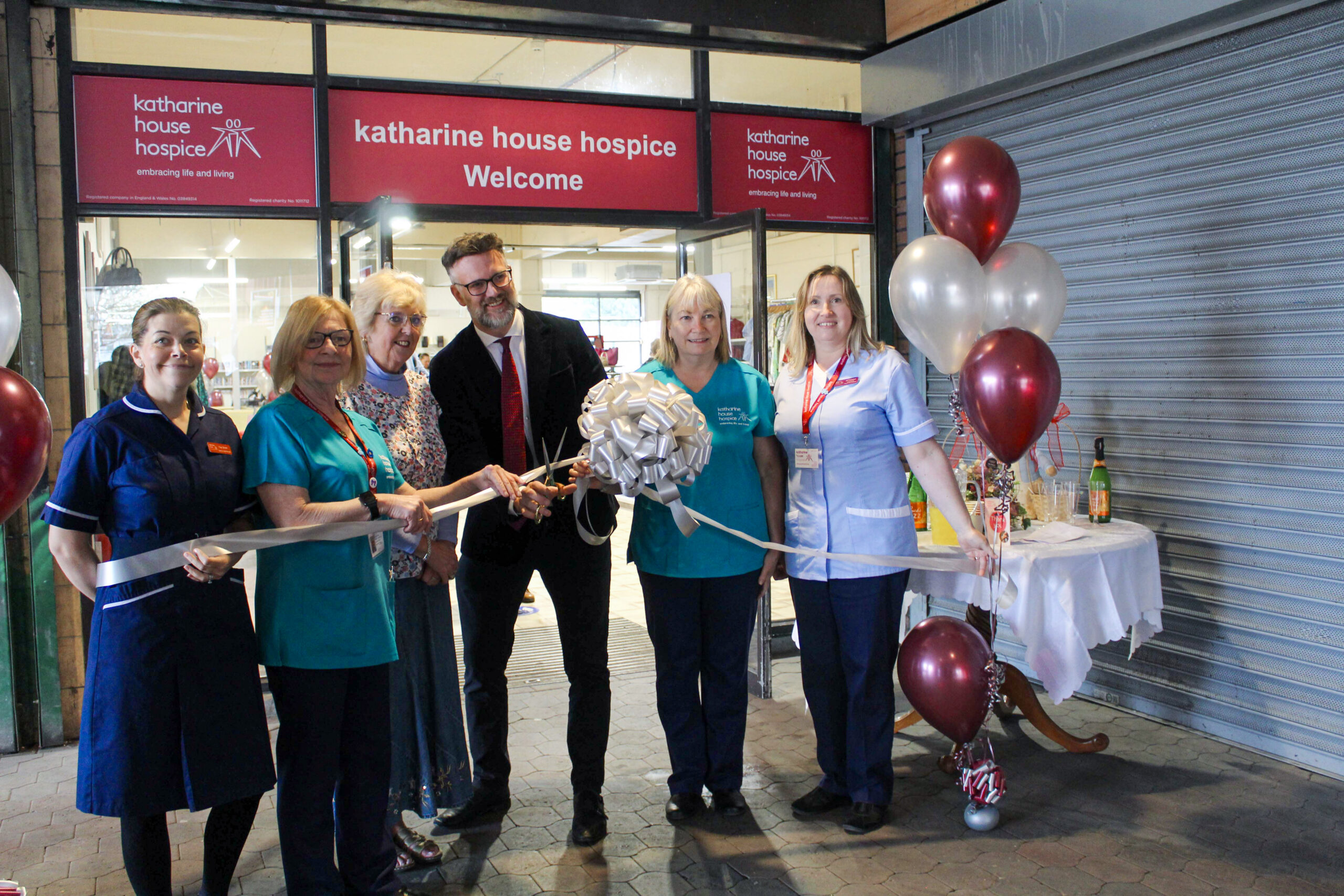 Tv presenter, Charles Hanson, and care staff with the ribbon to officially open the store.