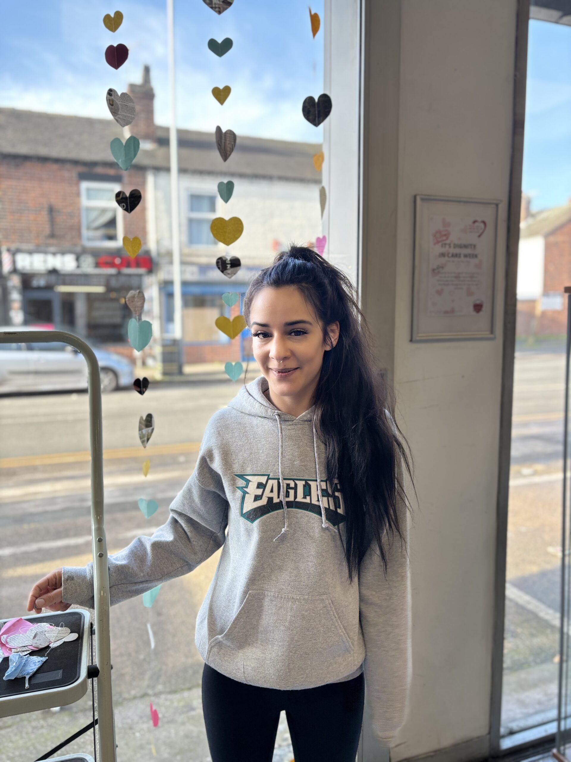 A woman with long black hair in a grey hoodie.
